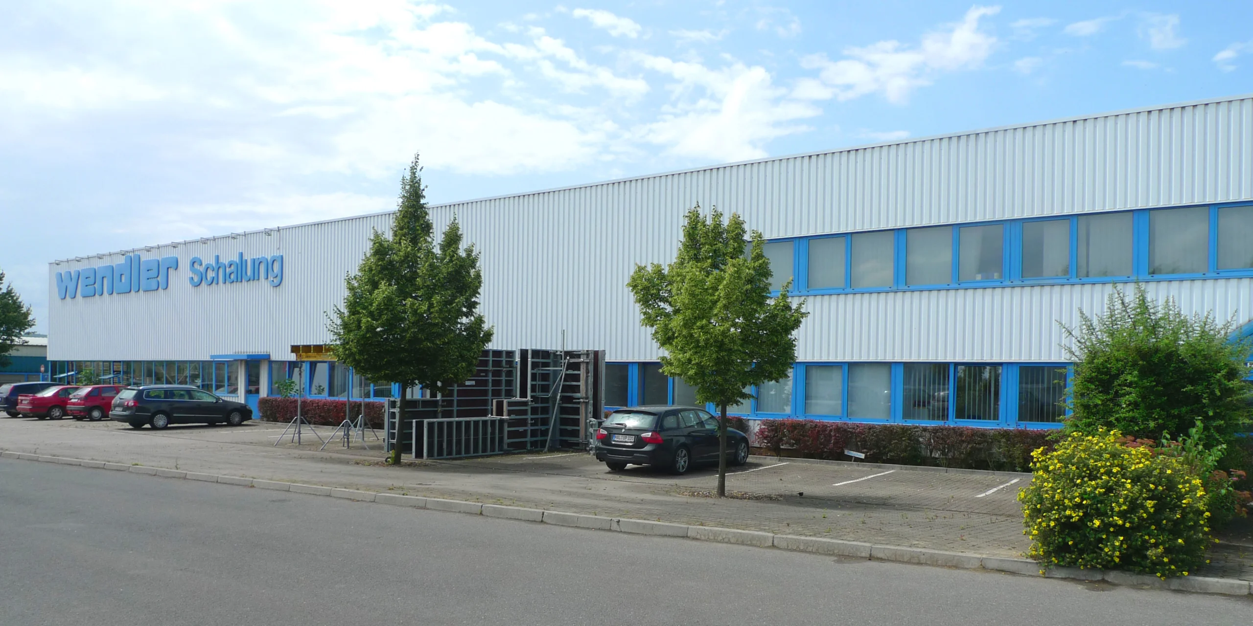 Firmengebäude von WENDLER Schalung mit Parkplatz und Bäumen