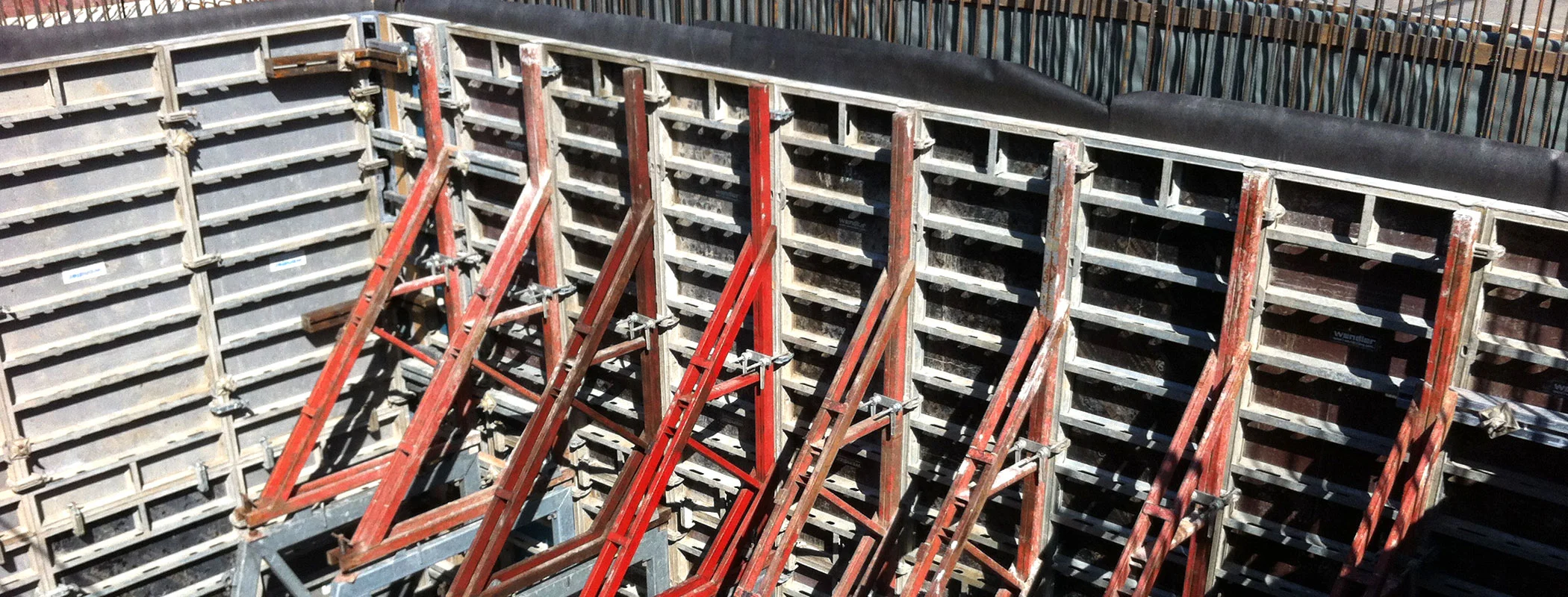 Wandschalung mit rot lackierten Richtstützen in dichter Reihe